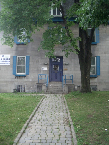 [Picture: Cobbled path through grass past tree to blue door in grey stone building.]