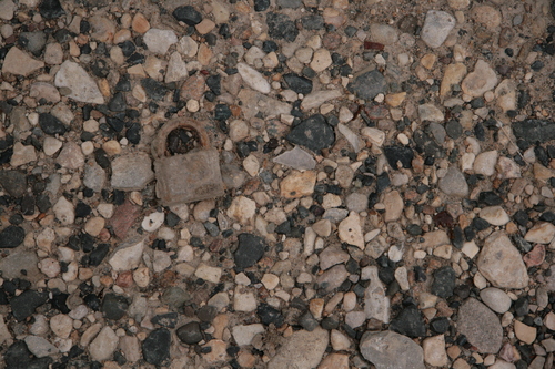 [Picture: Rusted padlock on small pebbles]